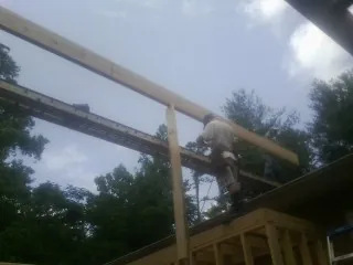 Carpenter setting a ridge beam over a new addition frame — Ice Dam Removal by Roofing Brothers in Aulander