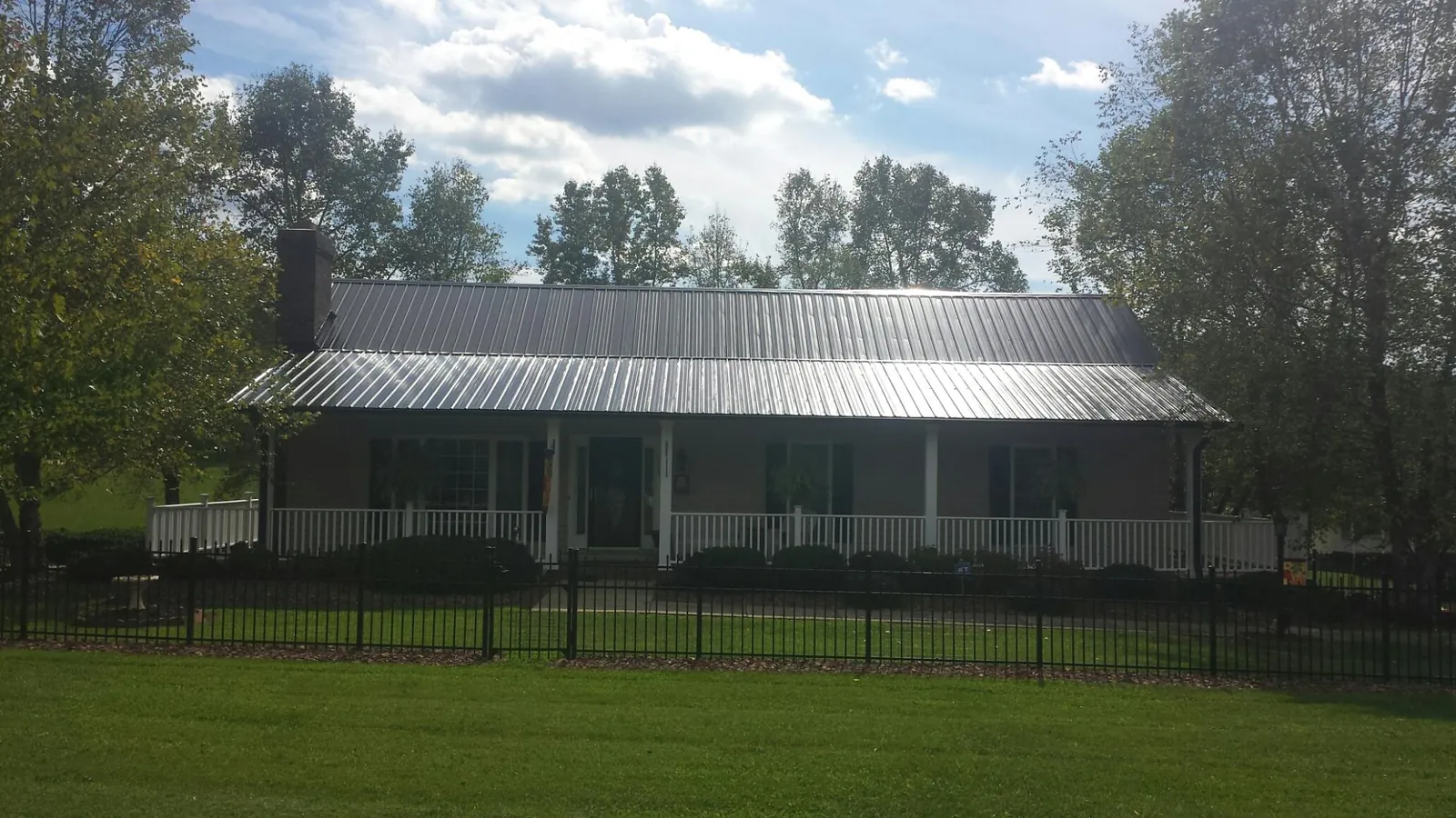 Gray metal roof on a brick ranch with a full width front porch — Gutter Guard Installation work by our crew in Aulander